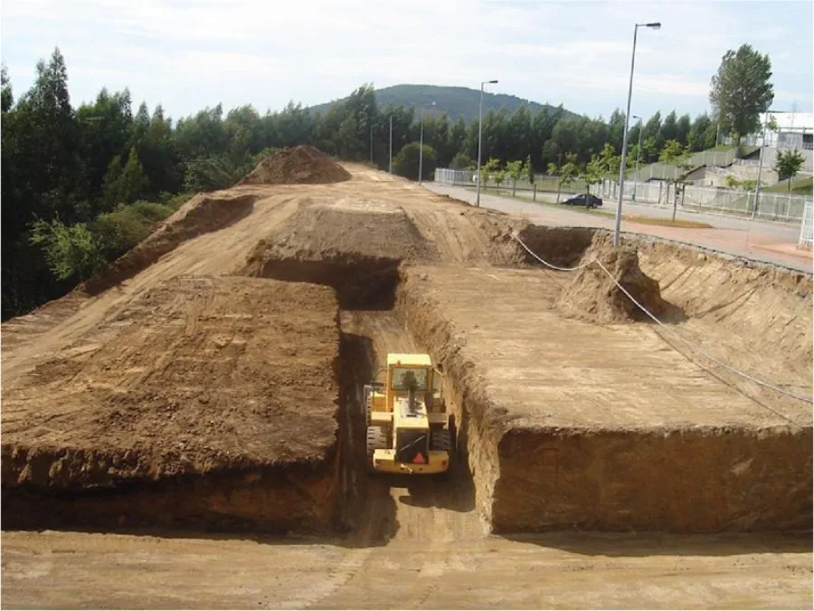 Chantier de terrassement : bouteur/chargeuse sur chenilles jaune au fond d'une tranchée large, plateforme de terrain décapée et nivelée sur plusieurs dizaines de mètres.